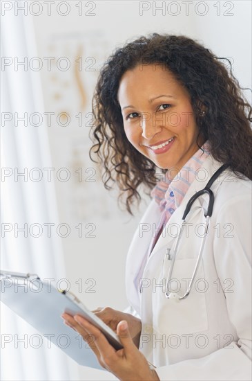 Hispanic doctor looking at medical chart in hospital