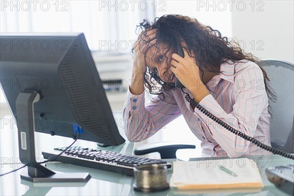 Hispanic businesswoman talking on telephone at desk
