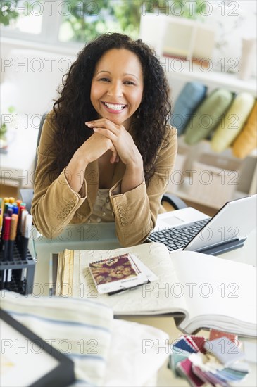 Hispanic businesswoman sitting at desk with laptop