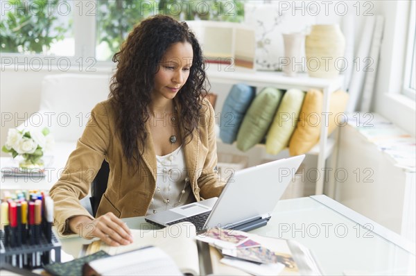 Hispanic businesswoman sitting at desk using laptop