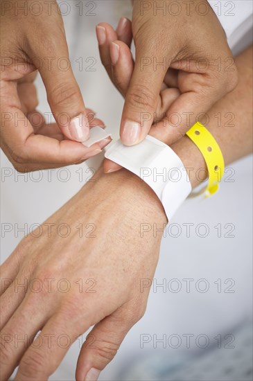 Nurse putting identification bracelet on patient in hospital