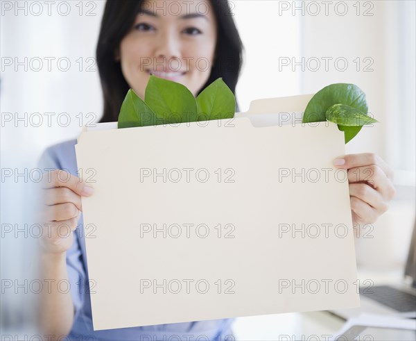 Japanese businesswoman holding folder containing leaves