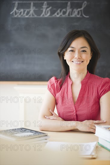 Japanese teacher sitting at desk in classroom