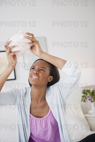 Black woman trying to get money out of piggy bank