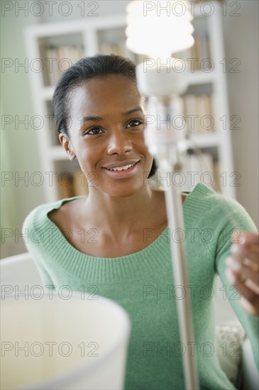 Black woman turning on CFL light bulb