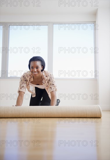 Black woman unrolling carpet in new home