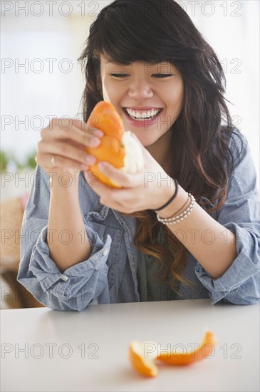 Pacific Islander woman peeling an orange