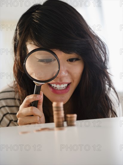 Pacific Islander woman examining pennies with magnifying glass