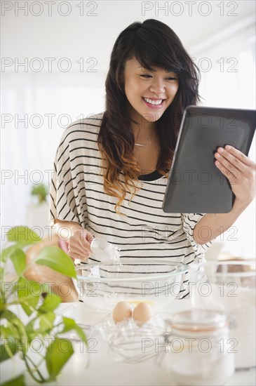 Pacific islander woman baking and using digital tablet