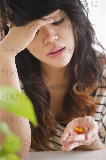 Pacific Islander woman looking at pills in her hand