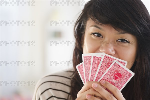 Pacific Islander woman covering her mouth with playing cards