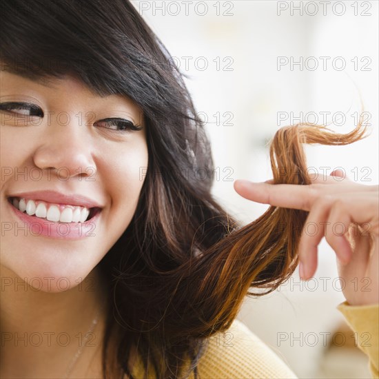 Pacific Islander woman looking at her hair