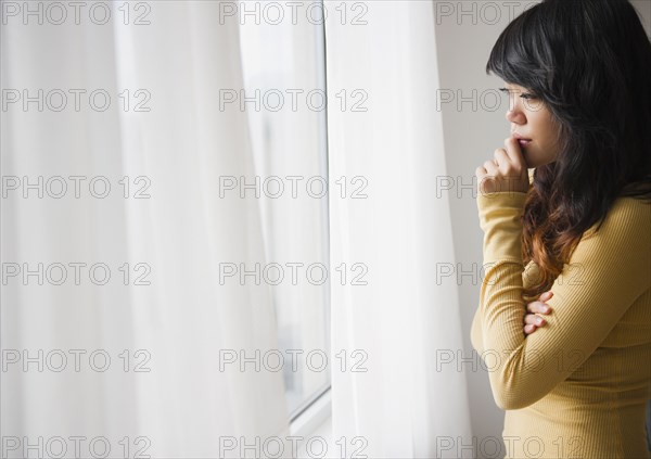 Pacific Islander woman looking out window