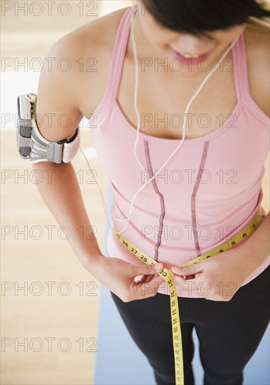 Pacific Islander woman measuring her waistline