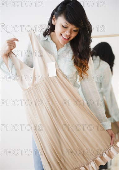 Pacific Islander woman looking at dress in store