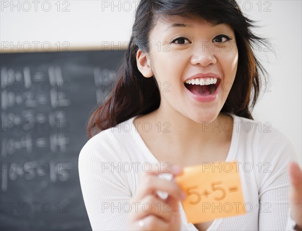 Pacific Islander teacher holding sticky note with math problem