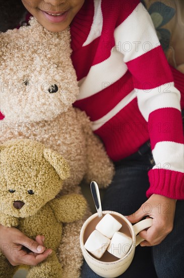 Mixed race girl with teddy bears drinking hot chocolate
