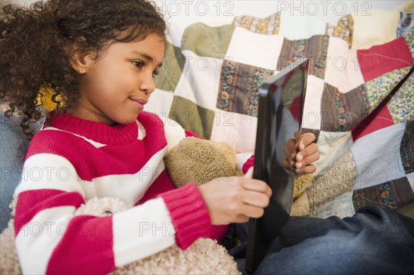 Mixed race girl sitting on sofa using digital tablet