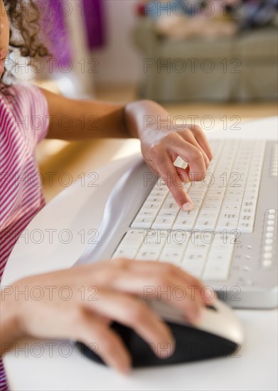 Mixed race girl using computer keyboard