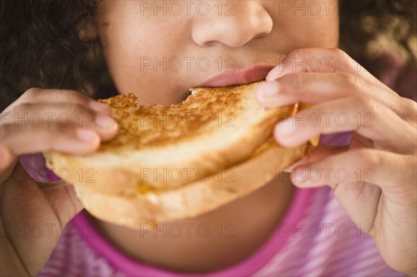 Mixed race girl eating sandwich