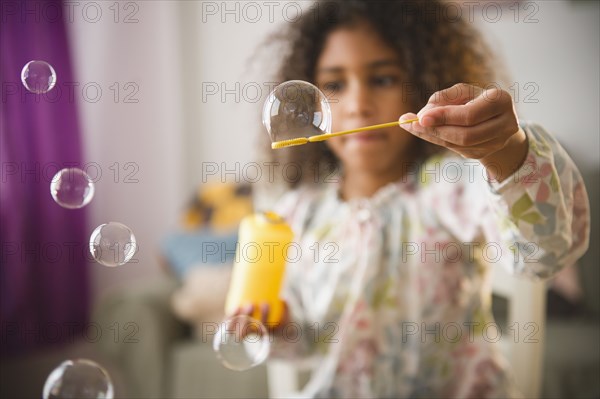 Mixed race girl playing with bubbles