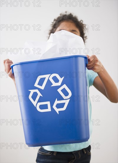 Mixed race girl carrying recycling bin