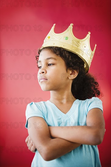 Mixed race girl with arms crossed wearing crown