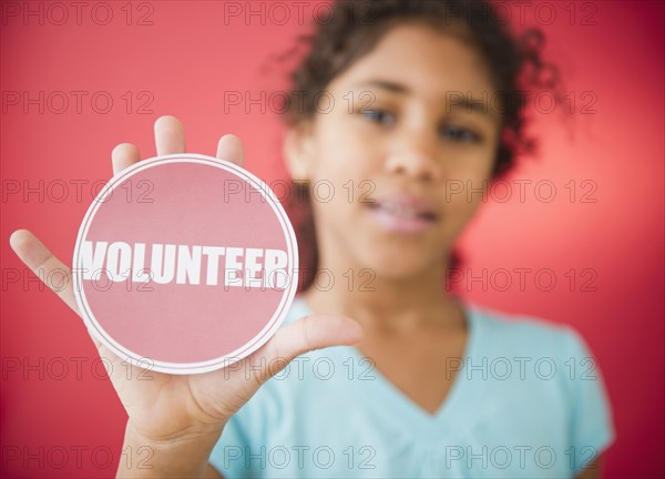 Mixed race girl holding volunteer sticker