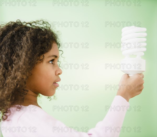 Mixed race girl holding CFL lightbulb