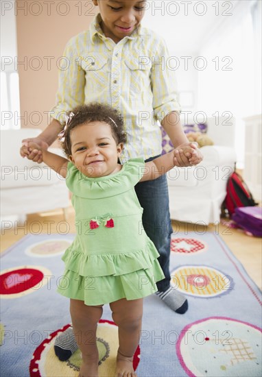 Black brother helping sister learn to walk