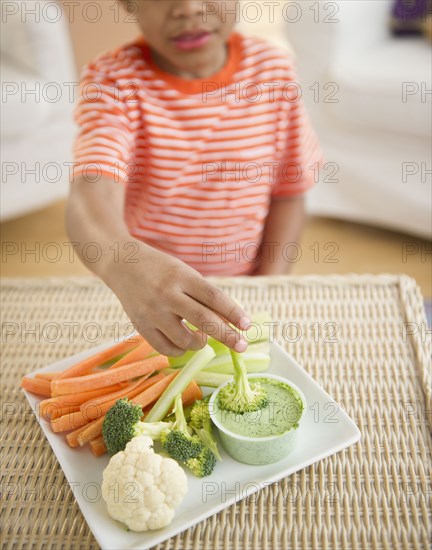 Black boy eating vegetables and dip