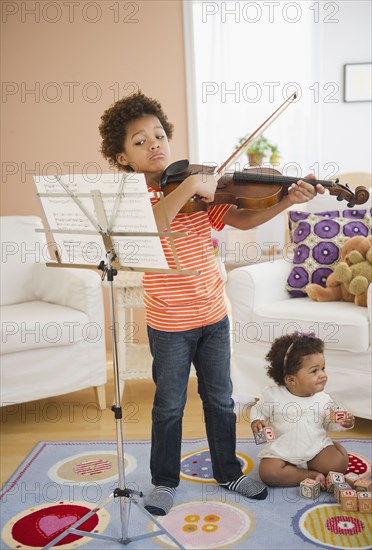 Black boy practicing violin in living room