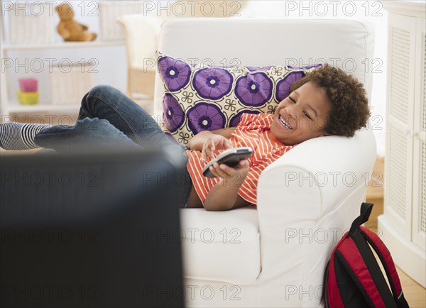 Black boy laying in chair watching television