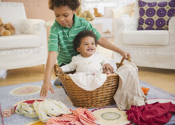 Black boy putting sister in laundry basket