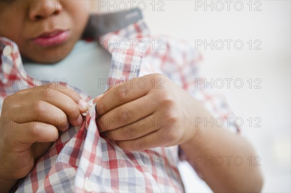 Black boy buttoning his shirt