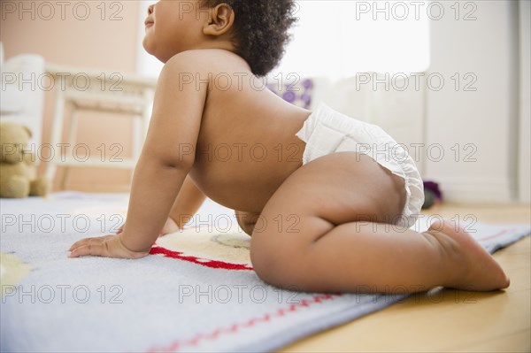 Black baby girl crawling on floor