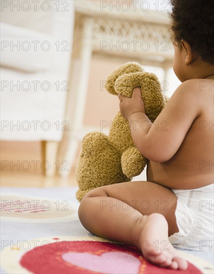 Black baby girl holding teddy bear