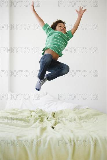 Black boy jumping on bed