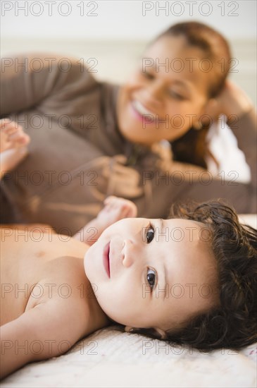 Mixed race mother laying on bed with baby