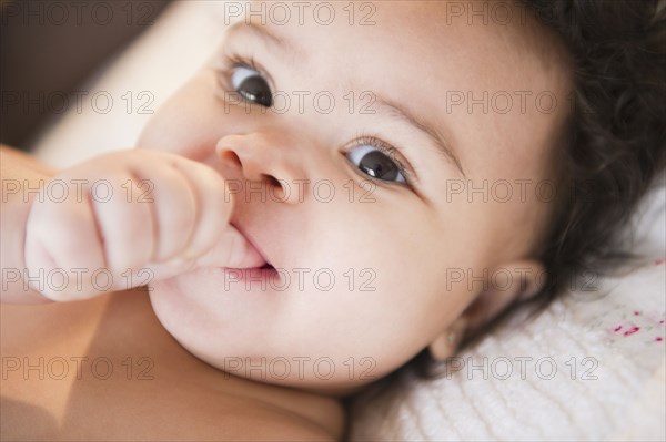 Close up of mixed race baby sucking thumb