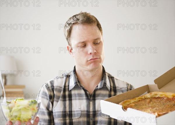 Caucasian man looking at pizza in box