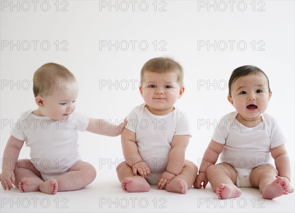 Three babies sitting on floor