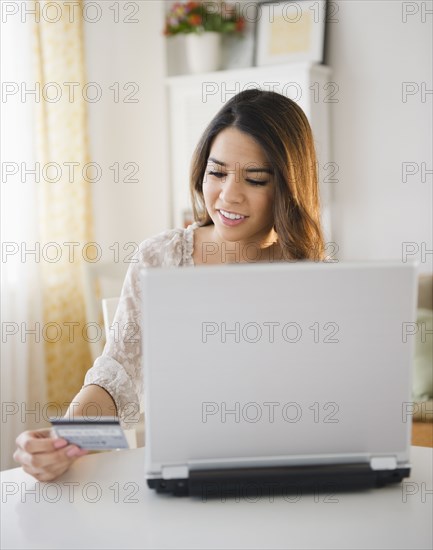 Hispanic woman shopping online with credit card