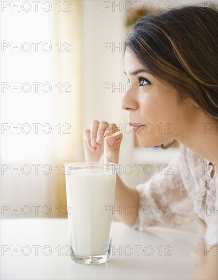 Hispanic woman drinking milk through straw