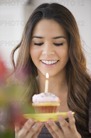 Hispanic woman blowing out cupcake candle