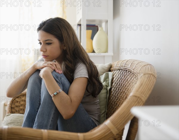 Hispanic woman sitting in chair thinking