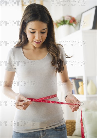 Hispanic woman measuring waistline