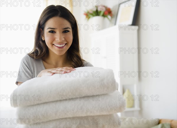 Hispanic woman holding stack of towels