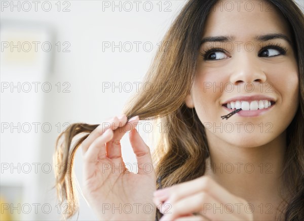 Hispanic woman with bobby pins in her mouth
