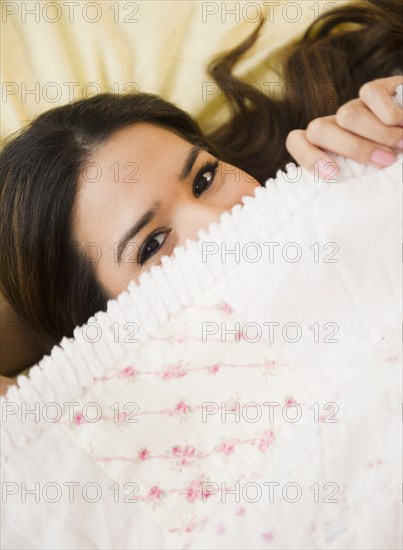 Playful Hispanic woman underneath blanket